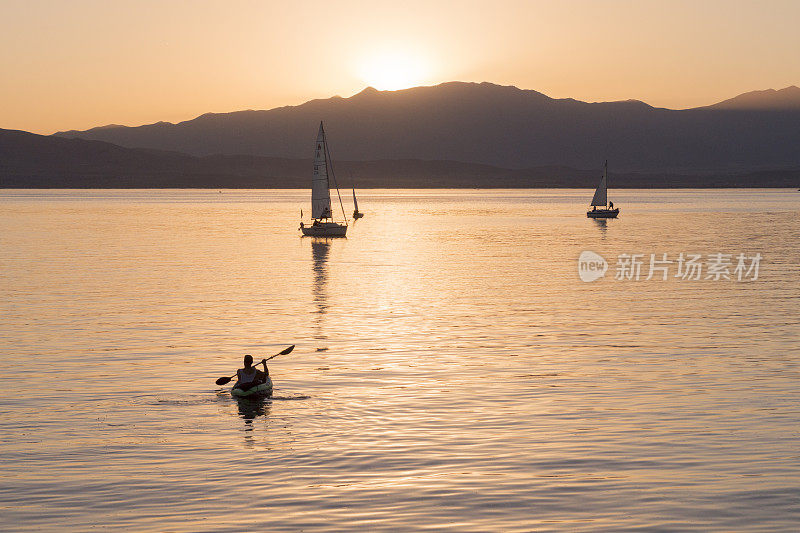 犹他州湖上的三艘帆船和一艘皮划艇的黄昏视图