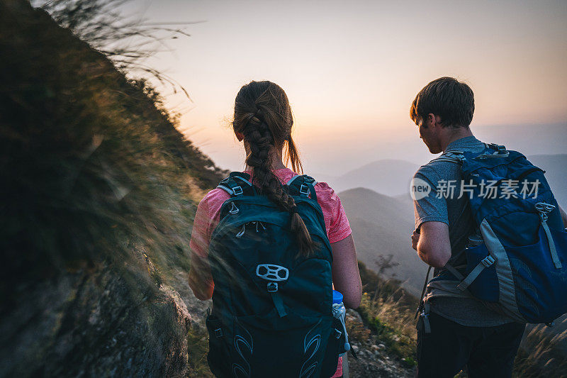 朋友们在日出时沿着阳光明媚的山脊徒步旅行