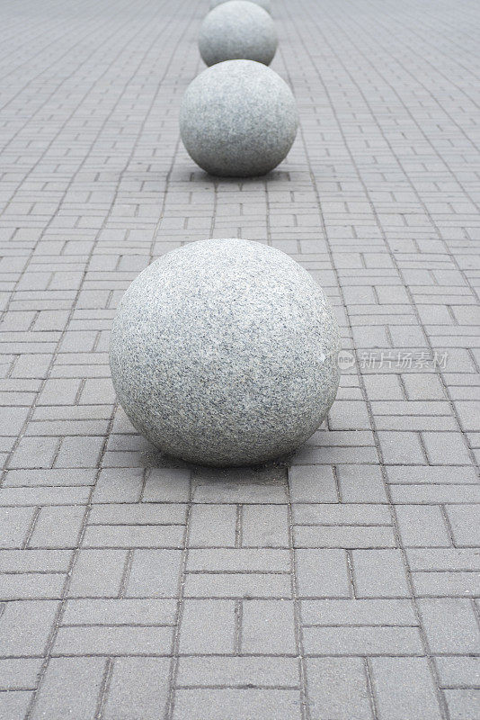 公园栏杆上的混凝土球体。公园的建筑。一个大石球躺在石头路面上