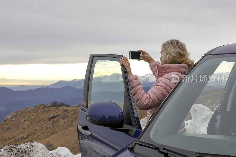 女人在车门旁放松，在山脊上