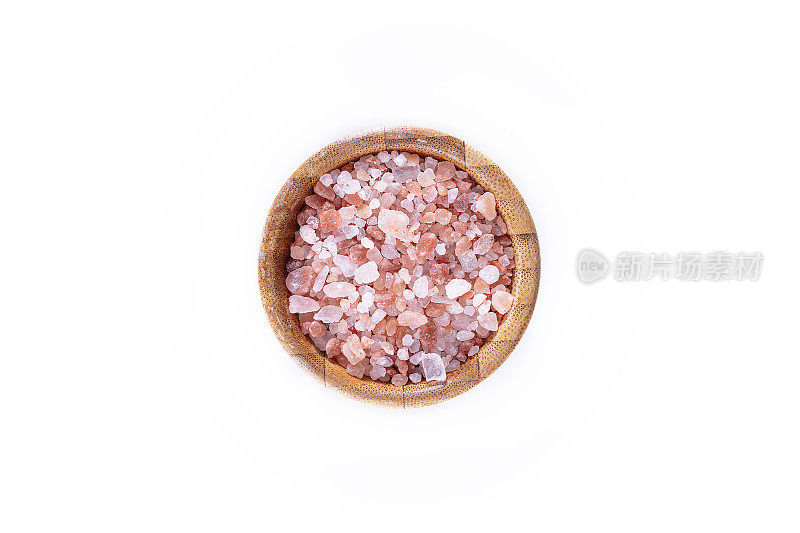 白色背景的木碗里放着粉红色的喜马拉雅海盐