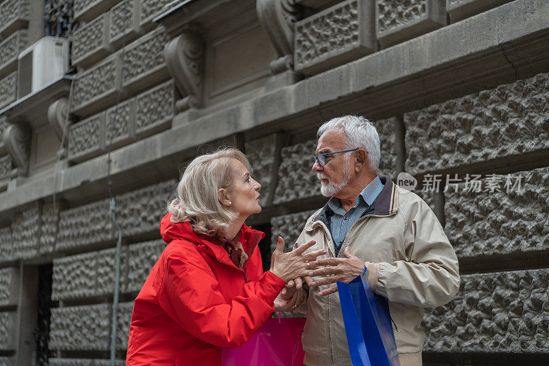 一对愤愤不平的退休老人在城市里散步并愤怒地辩论。