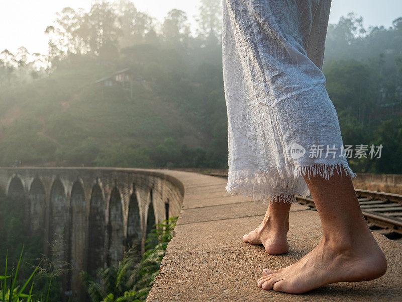 低角度的女人行走在古拱桥的边缘
