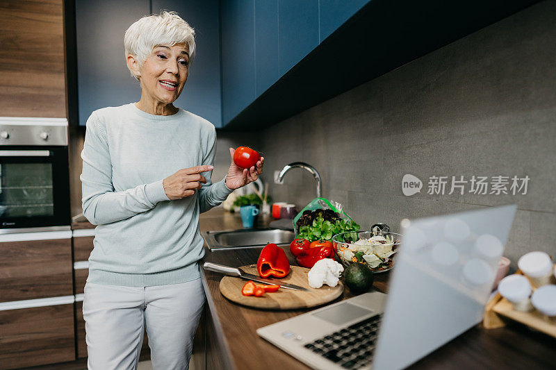 一位女士在厨房里用笔记本电脑打电话