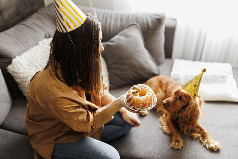 微笑的女人和她的狗在家里庆祝她的狗生日。