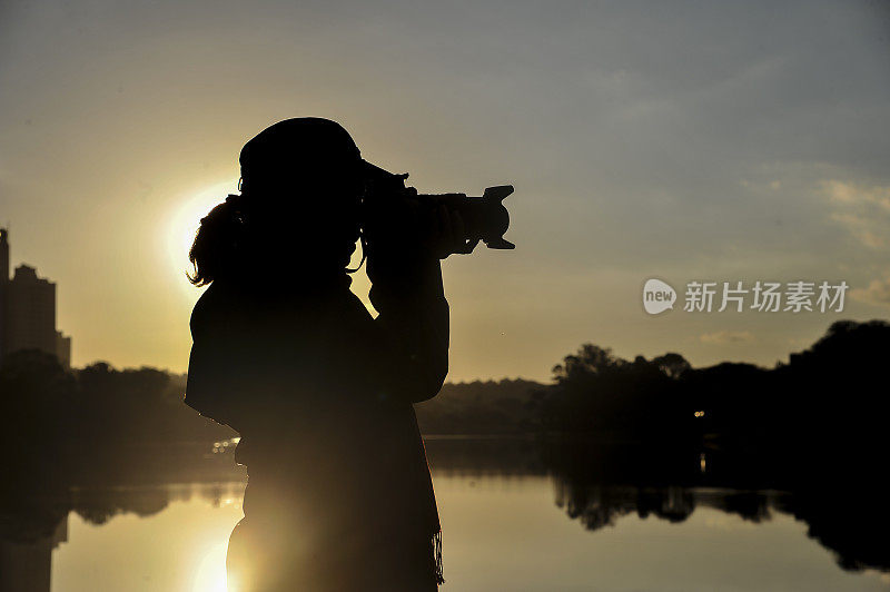 日落时在有湖的公园里拍摄的女人