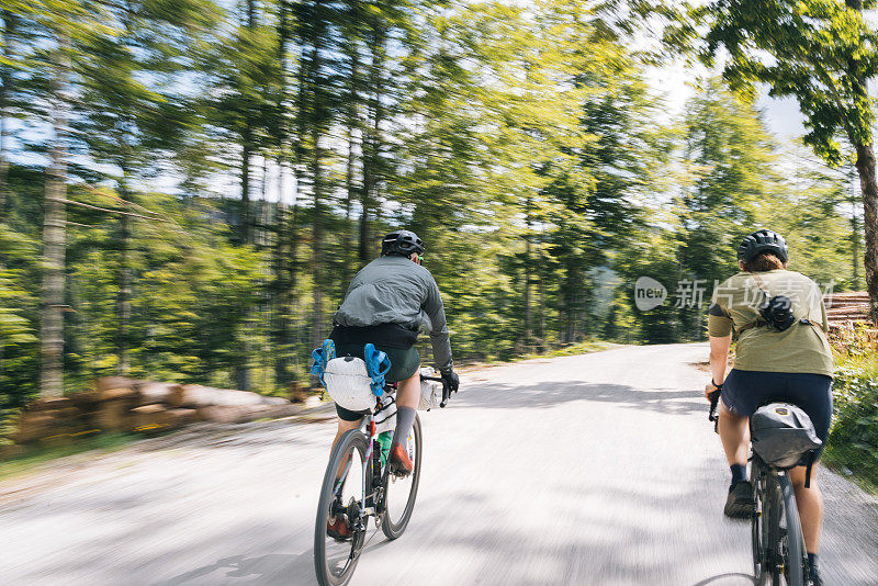 年轻人沿着阳光明媚的乡村公路骑自行车