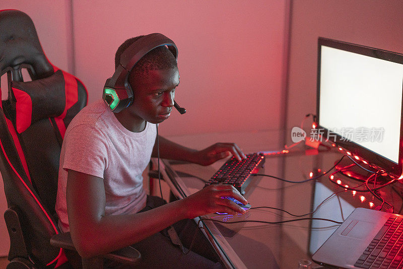 年轻的黑人男性玩家在车站使用台式电脑和笔记本电脑