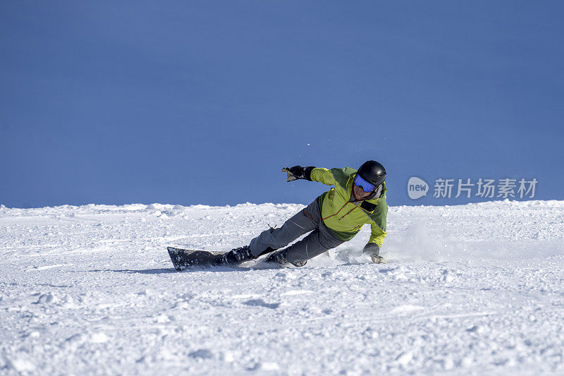 男子在滑雪板上切割滑雪坡