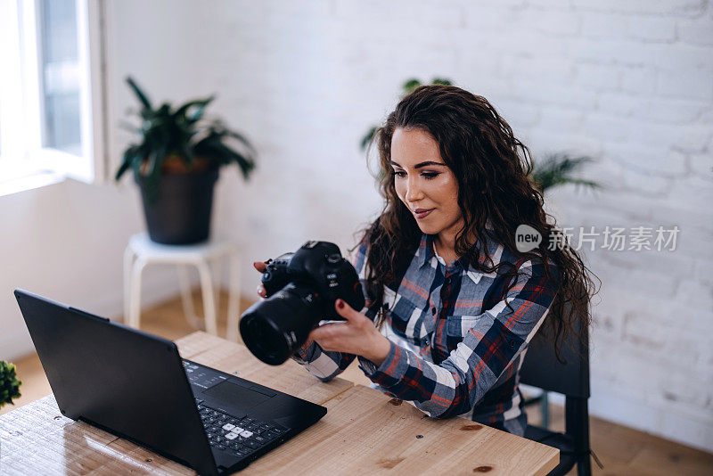 自由摄影师年轻女子与相机在家里编辑照片的笔记本电脑