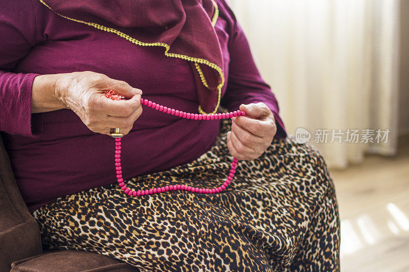 一位年长的穆斯林妇女正在祈祷，手里拿着念珠