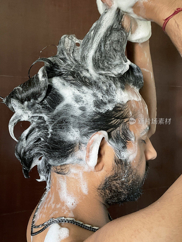 印度男子淋浴洗头的特写图片，使洗发水泡沫卷发，侧视图