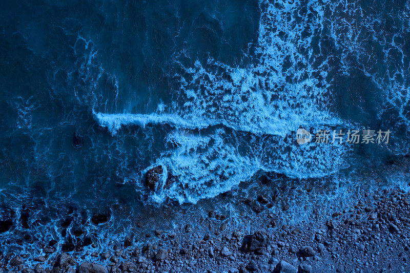 月光海滩:海浪在岩石海滩上溅起水花