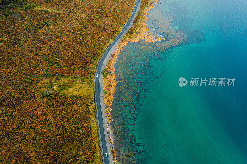 航拍的一辆汽车行驶在挪威翠绿色的海岸公路上