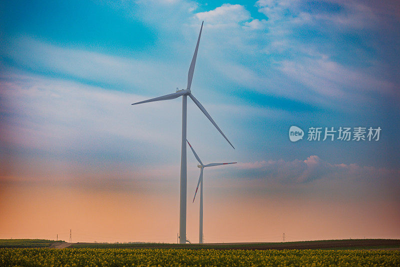 夕阳下，在蓝色和橙色天空的衬托下，农场上的风力涡轮机