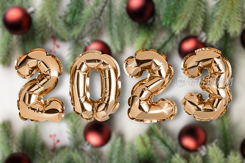 粉色2023气球在木制背景与圣诞闪亮的球，装饰，杉树树枝和礼物，平躺。新年庆祝概念背景