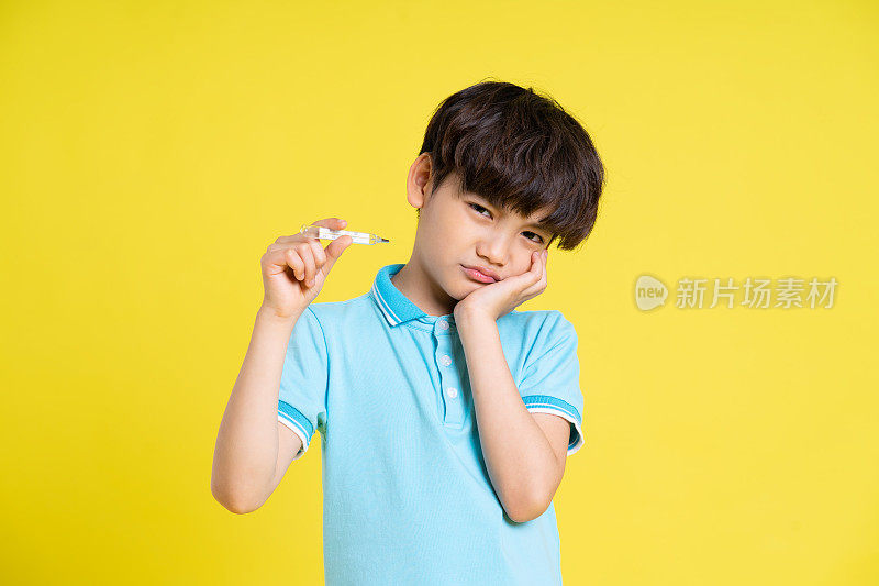 一个亚洲男孩在黄色背景上摆姿势的肖像