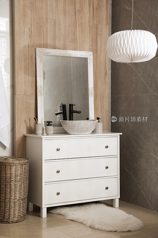浴室里有带水槽、镜子和洗漱用品的抽屉柜。室内设计