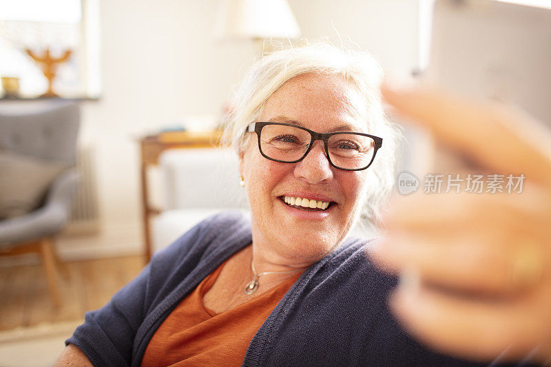 一位老年妇女在一所房子的客厅里用手机