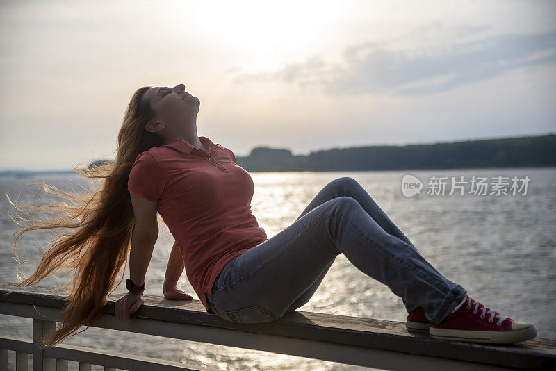 一个40多岁的女人在河边欣赏日落。