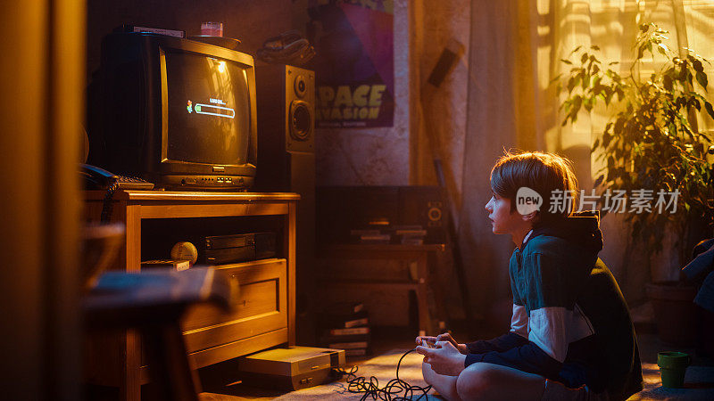 怀旧的童年概念:年轻的男孩在家里的复古电视机上玩老派街机视频游戏，房间内部的年代是正确的。孩子等待新的更难的水平加载。