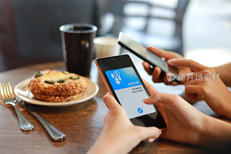 朋友们在咖啡馆共进早餐时，通过智能手机上的数字钱包应用程序分摊账单，收发餐费。有技术的智能银行。