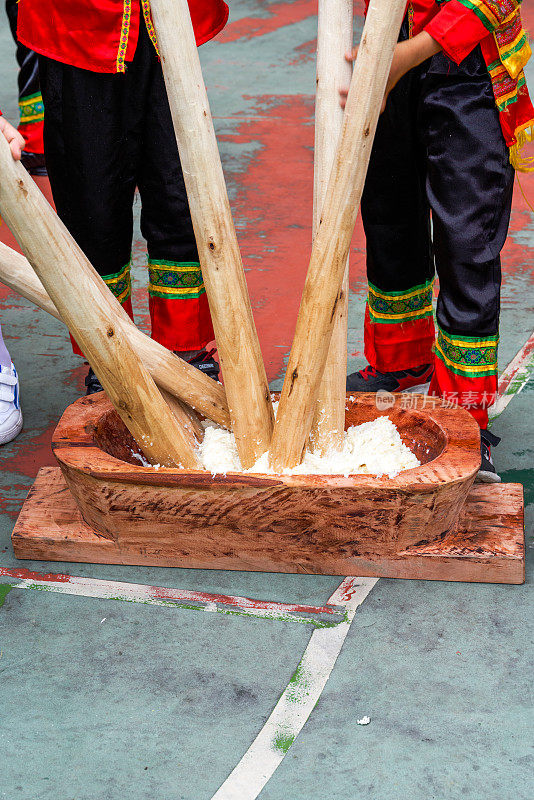 一群人用木棒敲打糯米，制作具有广西壮族特色的年糕