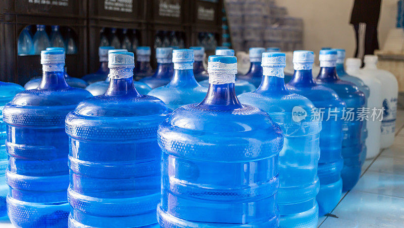 塑料大瓶或白色和蓝色加仑的纯净饮用水在生产线内准备销售。饮水厂，小本经营