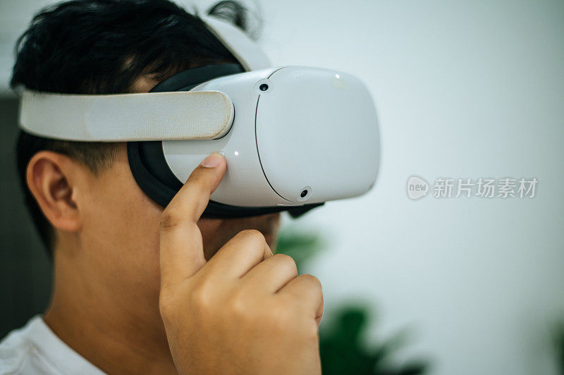 一个兴奋的亚洲男人在家里用VR眼镜探索虚拟现实