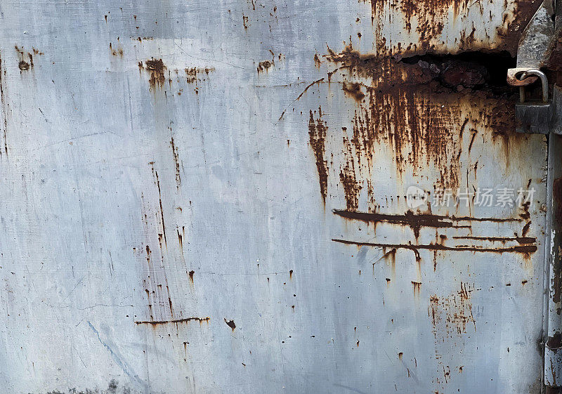 一扇锈迹斑斑的金属门的照片，上面有锈迹斑斑的把手，锈迹斑斑的金属门的表面和一把锈迹斑斑的锁。
