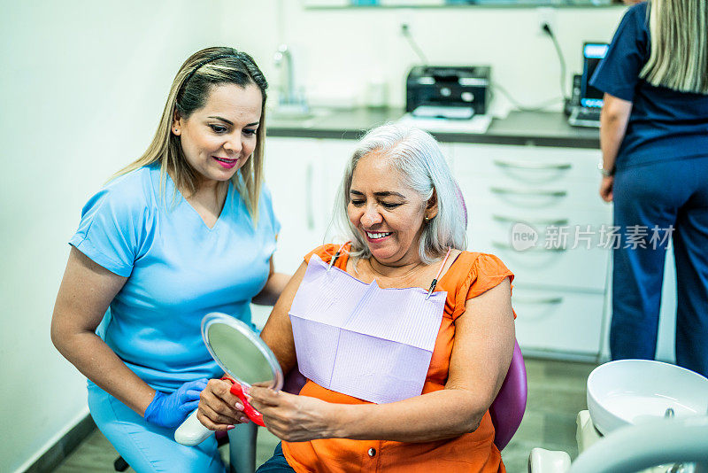 一个成熟的女人在牙医诊所用镜子看自己的牙齿