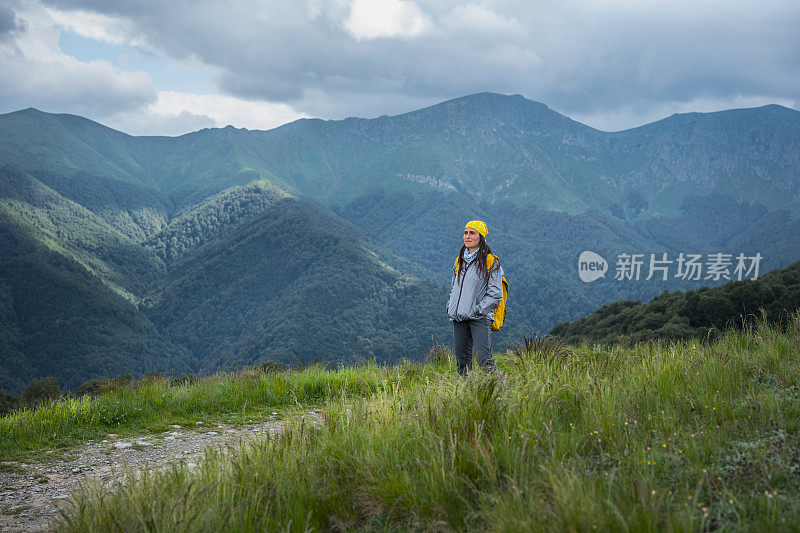 在一个阳光明媚的日子里在树林里徒步旅行的女游客。