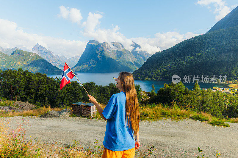 手持挪威国旗的女游客可以看到阿尔卑斯山山的美景