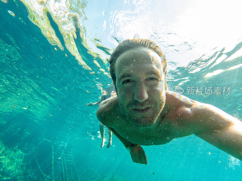 男子在清澈的水中游泳时在水下自拍