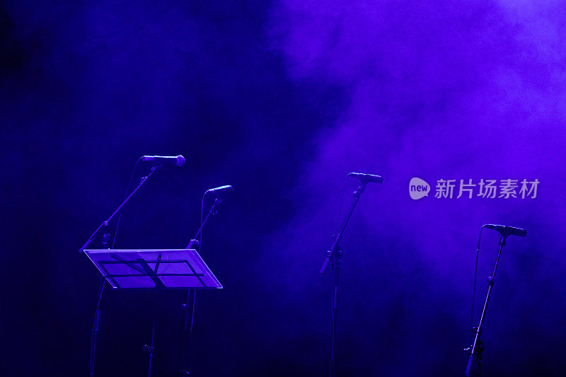 音乐会前舞台上的麦克风。紫色灯光的黑暗舞台