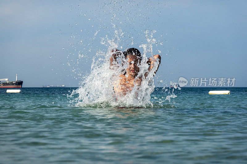 他用手在海里泼水。一个夏天的早晨。忒涅多斯岛。爱琴海北部，12岁的帅哥。长头发的