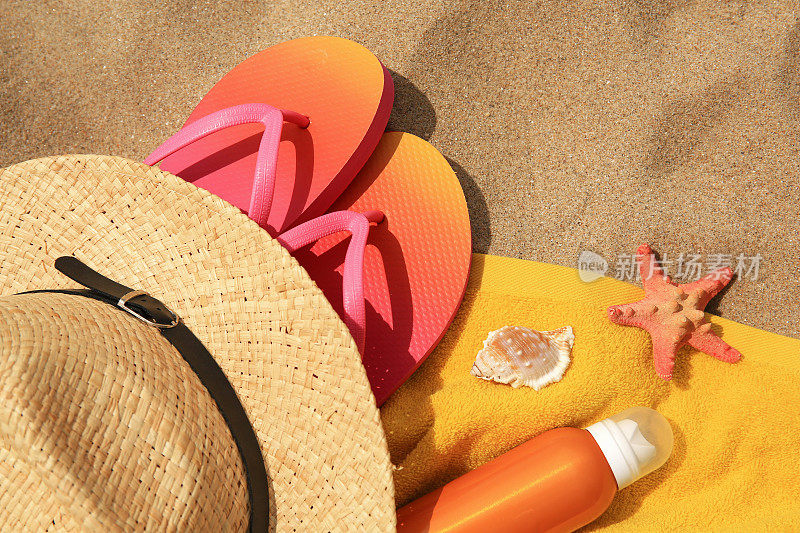 草帽、人字拖等沙滩物品放在沙滩上，平躺