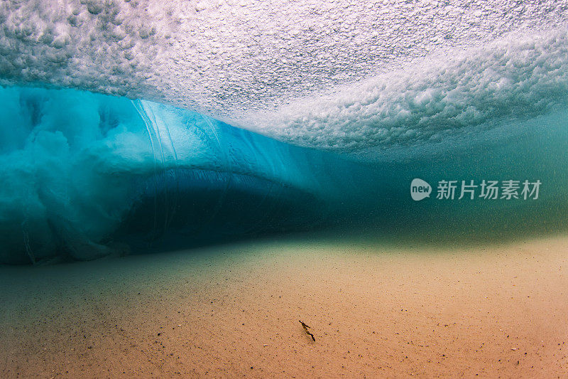 在清澈的海水中，海浪拍打着沙滩，水下的景色一览无余