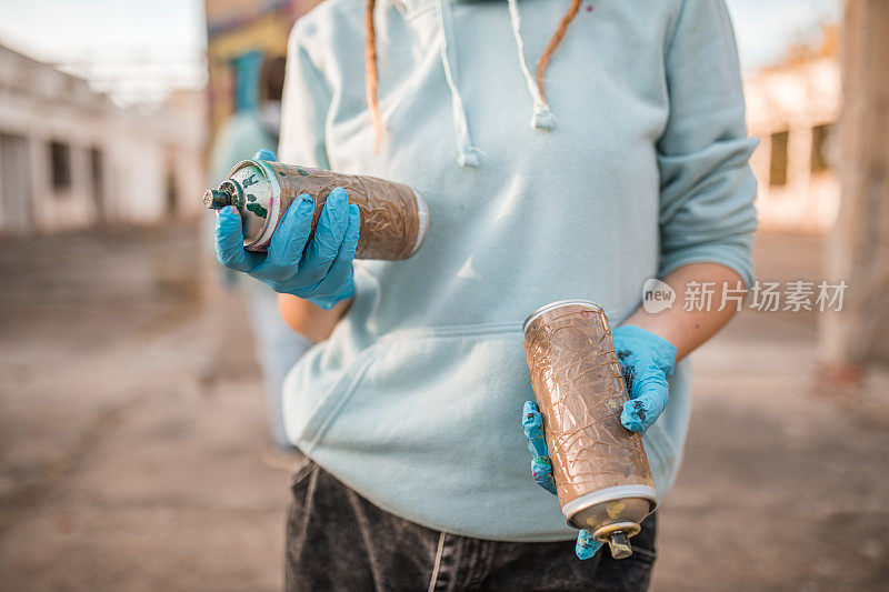 一个手持涂鸦喷雾器的女艺术家的手特写