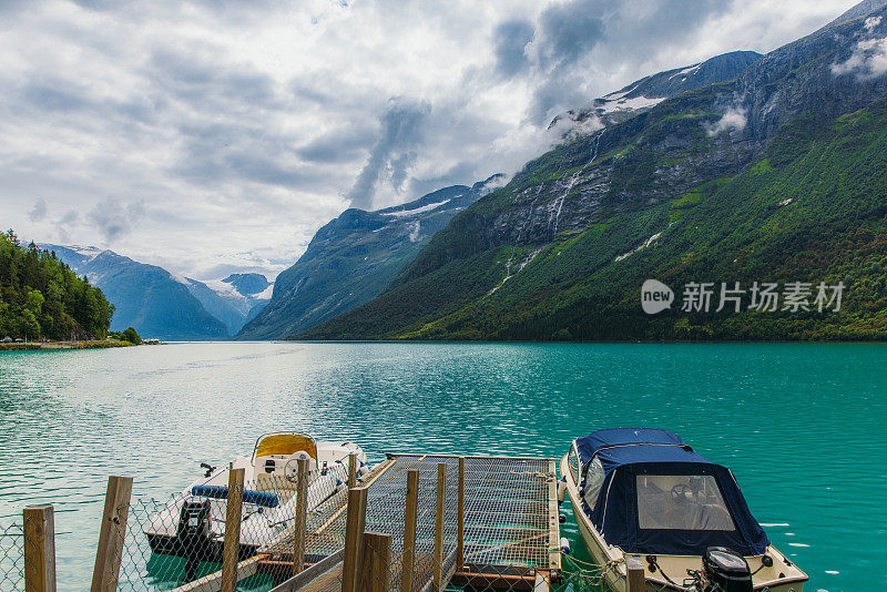 田园诗般的夏季景观船在水晶蓝湖与山景在挪威