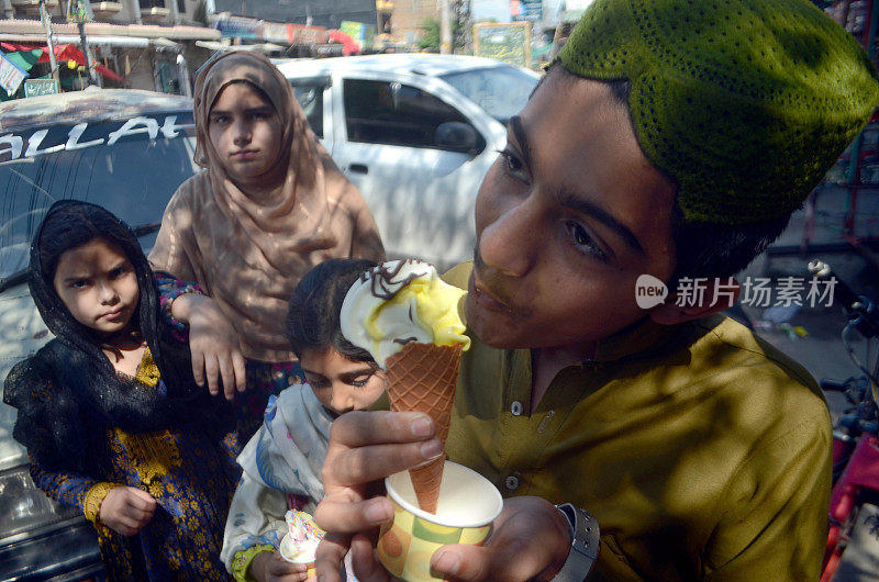 巴基斯坦，拉瓦尔品第:2024年4月21日，周日，拉瓦尔品第，炎炎夏日，孩子们吃着冰淇淋来抵御烈日