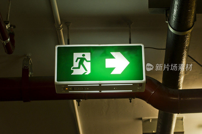 明亮的绿色出口标志悬挂在天花板上。