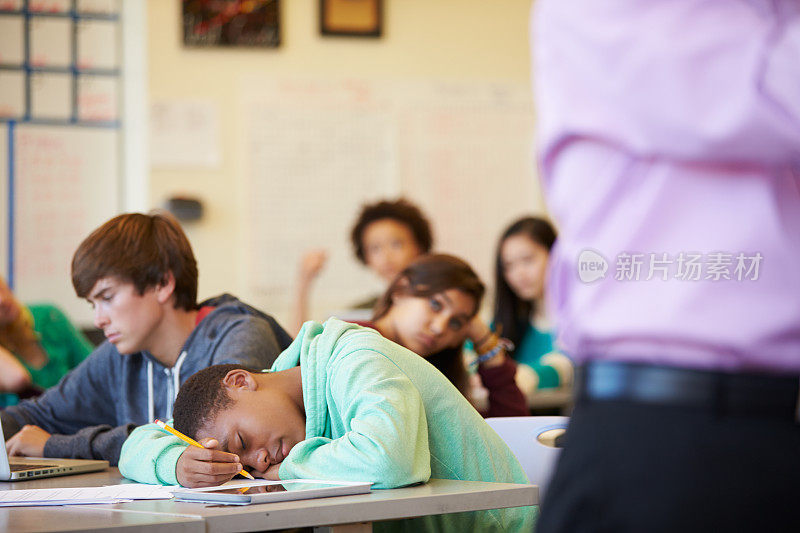 无聊的高中生瘫坐在教室的课桌上