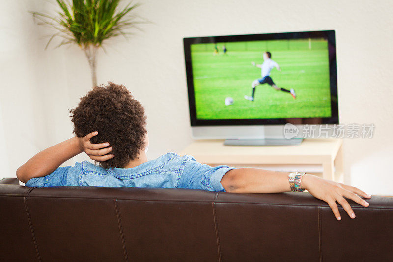 看电视转播足球运动，躺在沙发上休息的人