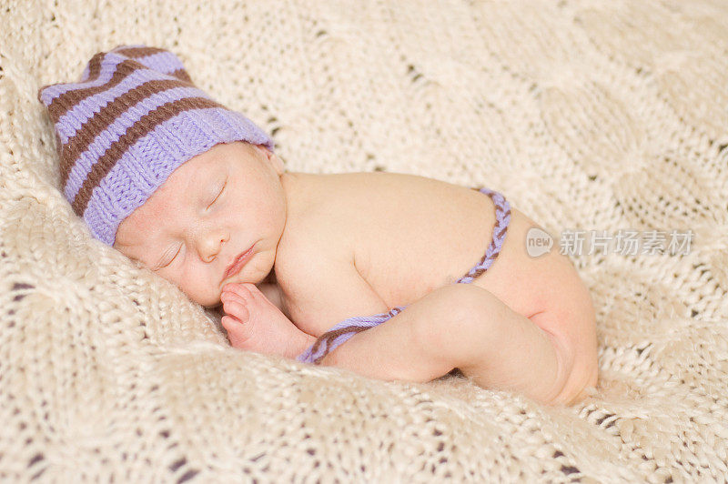 睡着的新生儿戴着针织精灵帽