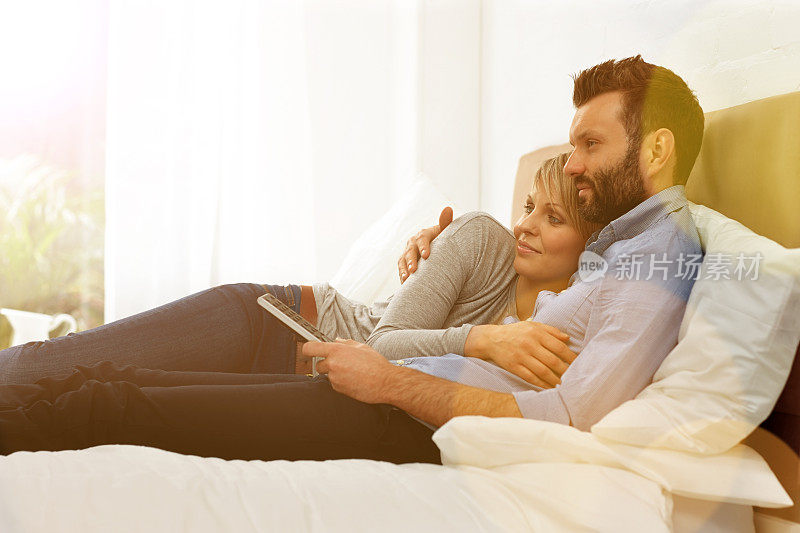 放松的年轻夫妇在卧室看电视