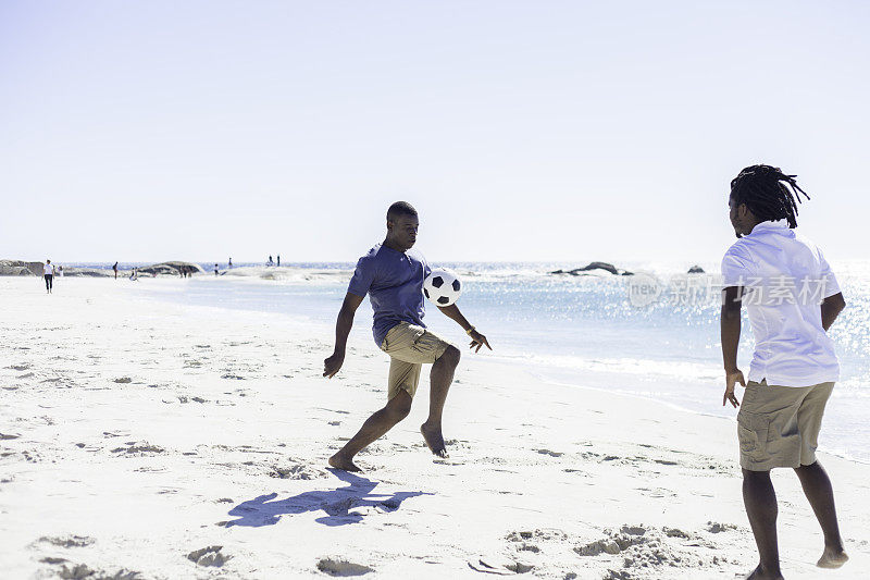 非洲雄性在海滩上玩球。