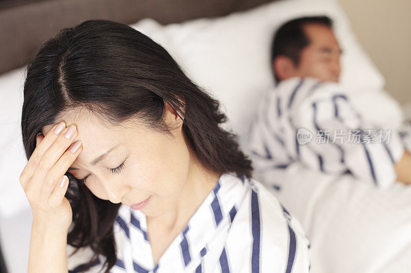 失眠的日本妇女头痛坐在床上