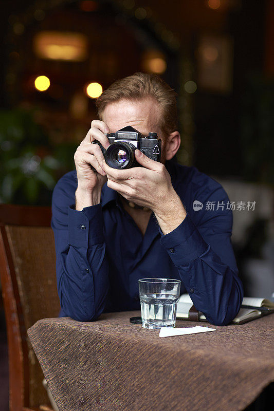 一个年轻人在咖啡馆用相机拍照
