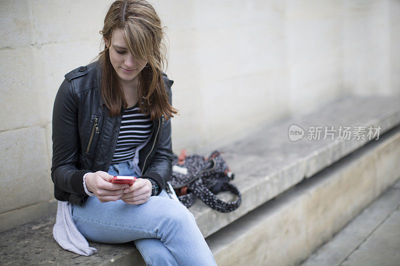 坐在公共场合拿着手机的年轻女人